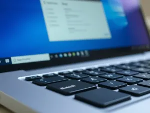Kobieta przy biurku z laptopem i smartfonem, korzystająca z usług online w domowym biurze.